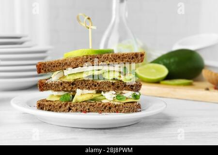 Sandwich vegetariano con avocado su pane di segale scuro su piatto bianco Foto Stock