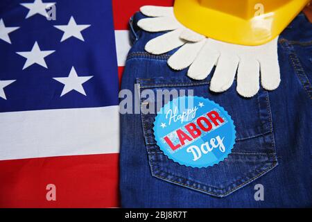 Concetto di giornata del lavoro. Casco giallo, guanti e jeans su sfondo bandiera degli Stati Uniti Foto Stock