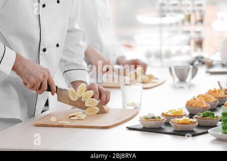 Chef che tagliano la banana su un asse di legno. Foto Stock