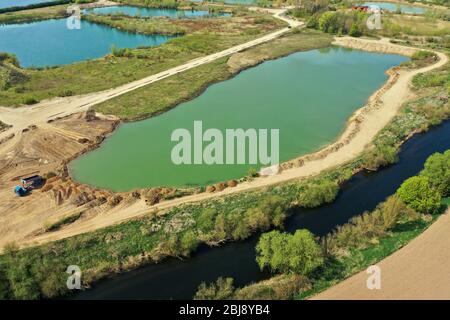 Veduta aerea di un attivo stagno ghiaia accanto al fiume Leine vicino Sarstedt, Germania, con un camion e mucchi di sabbia Foto Stock