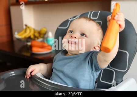 Bambino che tiene la carota in una sedia Foto Stock