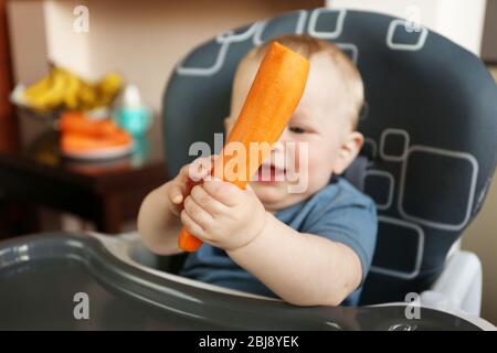 Bambino che tiene la carota in una sedia Foto Stock