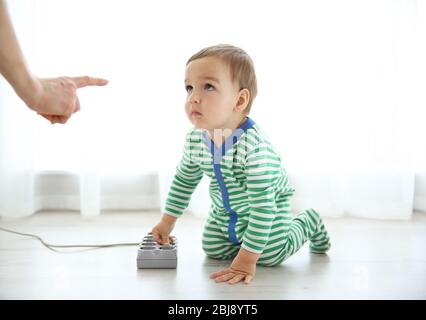 Madre che sgrida il suo bambino che sta giocando con la spina Foto Stock