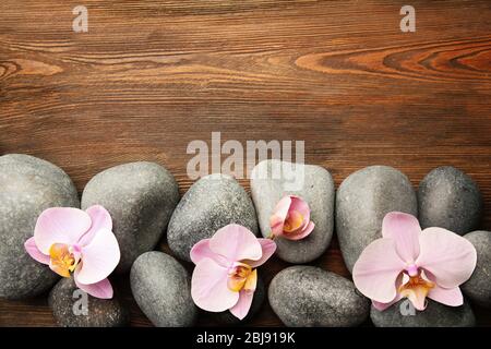 Pietre Spa e fiori di orchidee su sfondo di legno Foto Stock