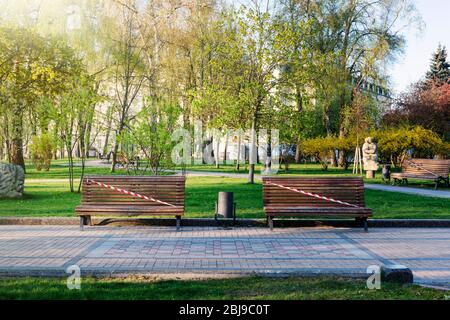 Kiev, Ucraina, parco cittadino vuoto durante la quarantena 2020. È vietato visitare i parchi, le panchine sono chiuse da nastro rosso e bianco. Foto Stock
