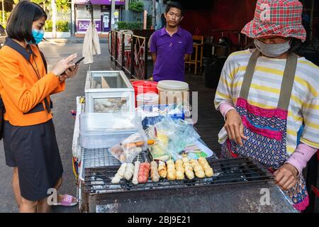 Venditore di cibo al cliente a Soi Cowboy durante la pandemia Covid 19 a Bangkok, Thailandia Foto Stock