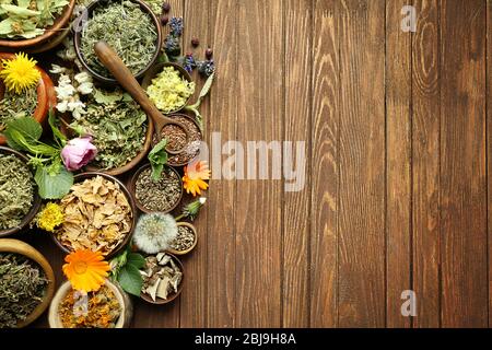 Selezione di erbe e fiori freschi in ciotole su sfondo di legno Foto Stock