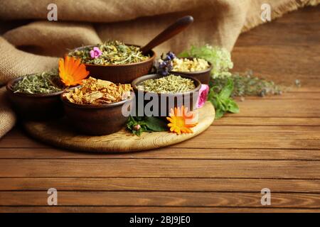 Selezione di erbe usate in medicina di erbe in ciotole su tavola di legno Foto Stock