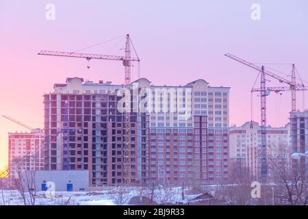 mattina d'inverno, la costruzione di case a più piani con gru a torre Foto Stock