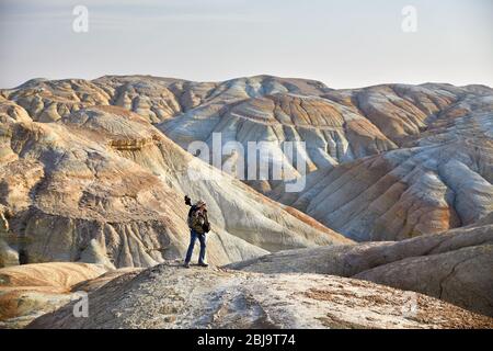 Turistico con fotocamera e zainetto nel surreale delle montagne del deserto Foto Stock