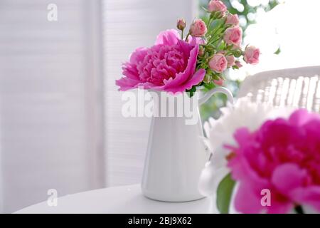 Bouquet di peonie in caraffa sul tavolo Foto Stock
