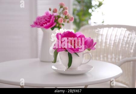 Bouquet di peonie in tazza sul tavolo Foto Stock