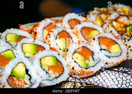 una selezione di diversi tipi di sushi californiani al salmone serviti in cima a uno skateboard Foto Stock