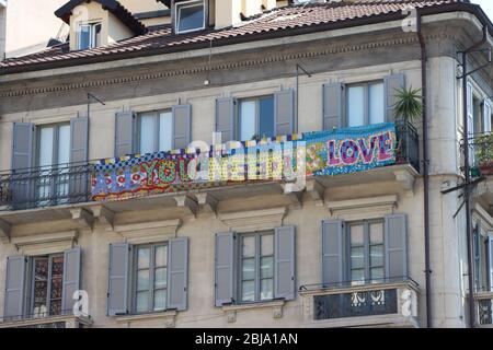 Un messaggio di speranza durante l'emergenza Covid 19 a Milano. Una bandiera si appende da un balcone che annuncia il bisogno universale di amore. Foto Stock