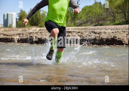 Gambe di runner chiudere fino al fiume con schizzi Foto Stock