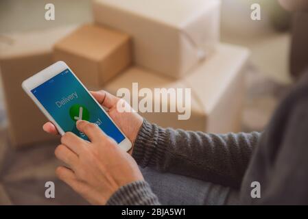 Avvio proprietario di piccole imprese che lavora con il telefono. Venditore freelance donna controllare l'ordine del prodotto. Imballaggio delle merci per la consegna al cliente. Vendita online. E Foto Stock