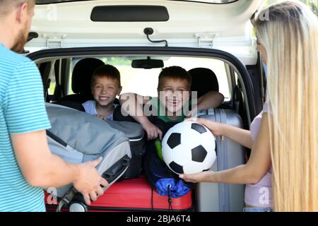 Genitori che mettono i bagagli nel bagagliaio dell'auto Foto Stock