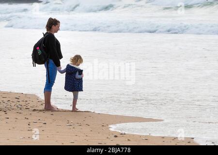 Madre e bambino che si trovano sulla costa di Fistral a Newquay in Cornovaglia. Foto Stock