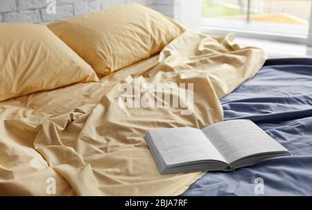 Libro aperto su letto sminuzzato in camera Foto Stock