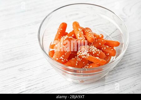 Carote cotte per bambini con sesamo in ciotola di vetro su sfondo di legno chiaro Foto Stock