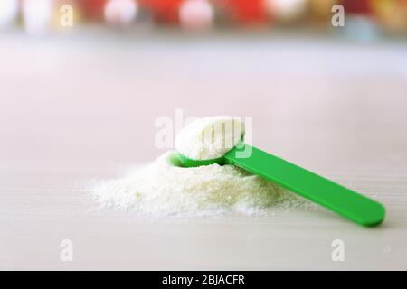 Latte per bambini in cucchiaino verde su fondo di legno Foto Stock