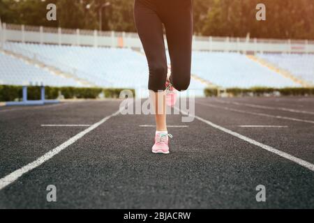 Donna che corre in sneakers rosa su uno stadio Foto Stock