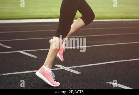 Donna che corre in sneakers rosa su uno stadio Foto Stock