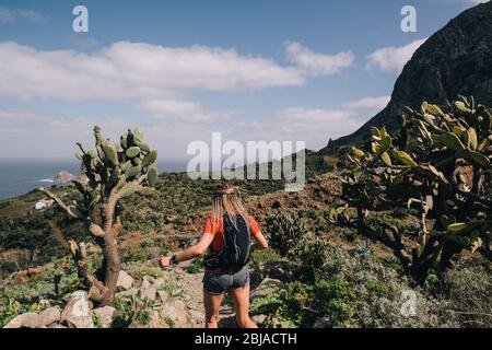 Donna corre fondo su un sentiero in montagna a Isole Canarie. Vista sull'oceano Foto Stock