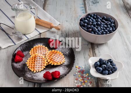 Tradizionali waffle belgi con frutta fresca e latte. Tavolo da cucina rustico. Foto Stock