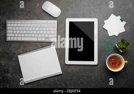 Tablet con tazza di caffè e strumenti da ufficio su sfondo grigio Foto Stock