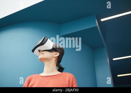 Giovane donna in piedi in occhiali virtuali è in realtà virtuale Foto Stock