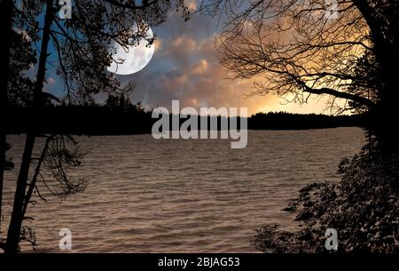Immagine di un lago durante il tramonto bello con la luna sul cielo. Foto Stock