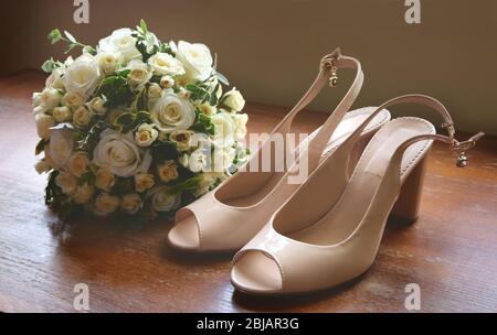 Scarpe da matrimonio e bouquet di rose bianche sul pavimento Foto Stock