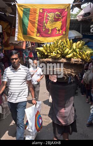 dh COLOMBO SRI LANKA persone locali visualizzati in donna di mercato con la bandiera leone delle banane dello sri lanka Foto Stock