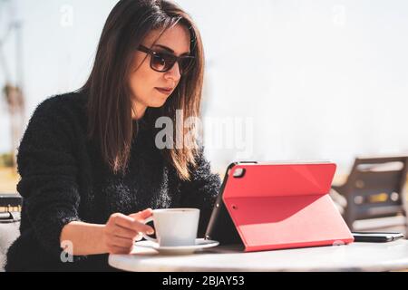 Bella giovane donna con Zoom videoconferenza chiamata tramite tablet. Zoom riunione chiamata. Durante Covid-19, pandemia di coronavirus Foto Stock