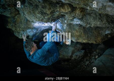 L'uomo sta facendo un masso nella grotta di Twardowski. Bouldering nella roccia. Grotta di Twardowski Foto Stock