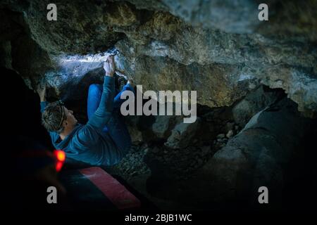 L'uomo sta facendo un masso nella grotta di Twardowski. Bouldering nella roccia. Grotta di Twardowski Foto Stock