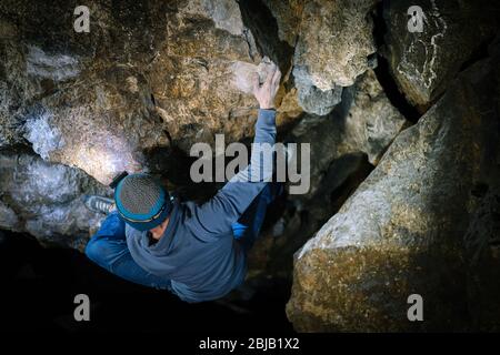 L'uomo sta facendo un masso nella grotta di Twardowski. Bouldering nella roccia. Grotta di Twardowski Foto Stock