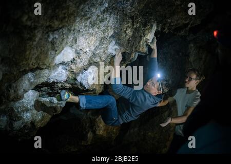 L'uomo sta facendo un masso nella grotta di Twardowski. Bouldering nella roccia. Grotta di Twardowski Foto Stock