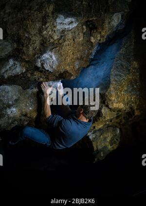 L'uomo sta facendo un masso nella grotta di Twardowski. Bouldering nella roccia. Grotta di Twardowski Foto Stock