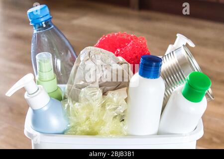 Cestino bianco con spazzatura domestica. Bottiglie di plastica e carta in un cestino. Cestino con spazzatura in cucina. Foto Stock