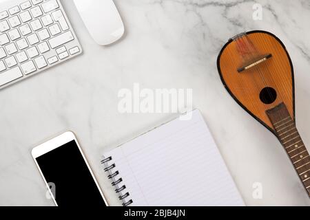 Telefono cellulare, tastiera, mouse, notebook e baglamas - bouzouki, uno strumento musicale. Foto Stock