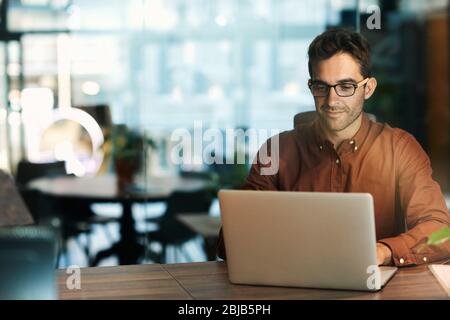 Uomo d'affari che usa un notebook mentre lavora in ufficio Foto Stock