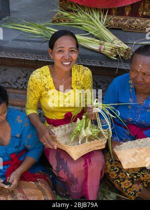 dh Balinese Batuan tempio Asia BALI INDONESIA donne indù Tipat Pacchetti di riso Ketupat pacchetto indonesiano donna sorridente sud-est asiatico offerte Foto Stock