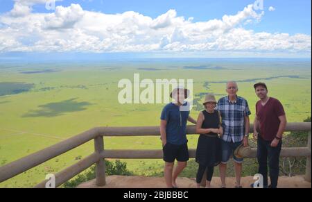 La famiglia che gode di un pasto safari sulla scogliera, Masai Mara Reserve, Kenya Foto Stock