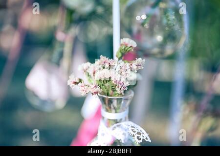 Mini vaso con fiori appesi su nastri esterni Foto Stock