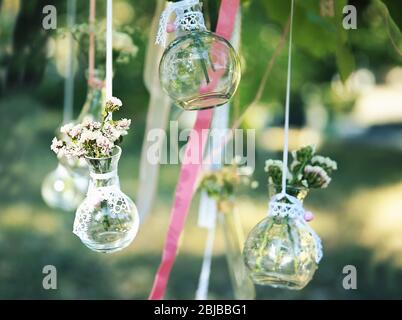 Mini vasi con mazzi di fiori appesi su nastri esterni Foto Stock