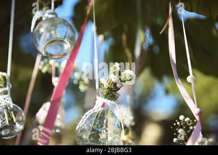 Mini vasi con mazzi di fiori appesi su nastri esterni Foto Stock