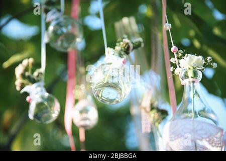 Mini vasi con mazzi di fiori appesi su nastri esterni Foto Stock