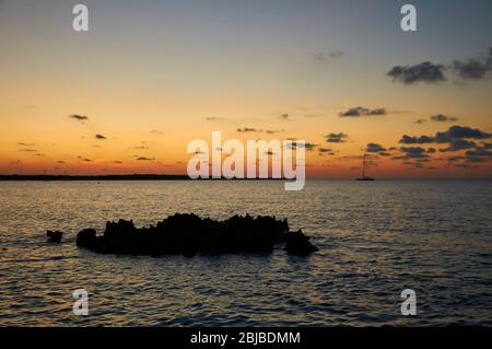 Tramonto con la silhouette rocciosa e barche a vela vicino Caló de s'Oli nel Parco Naturale di Ses Salines (Formentera, Isole Baleari, Mar Mediterraneo, Spagna) Foto Stock